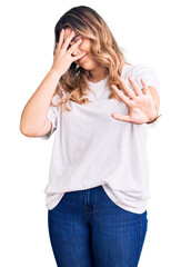 Young caucasian woman wearing casual clothes covering eyes with hands and doing stop gesture with sad and fear expression. embarrassed and negative concept.