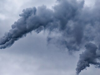 This is a photo of a dark gray smoke cloud billowing against a lighter gray sky.