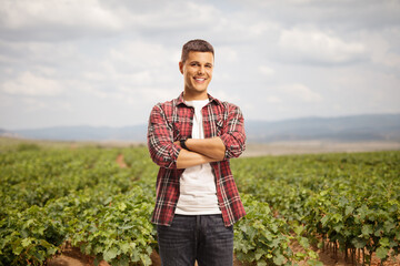 Man standing with crossed arms at a vineyard