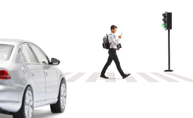 Male student in a college uniform crossing a street and looking at a smartphone