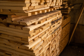 Raw stacked wooded planks drying in the lumber warehouse. Wooden planks in close-up. Background of boards. Wood timber stack of wooden blanks construction material. Industry.
