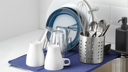 Drying kitchenware and cutlery stand by the sink.