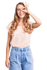 Fototapeta premium Young beautiful caucasian woman with blond hair wearing casual clothes doing ok gesture with hand smiling, eye looking through fingers with happy face.