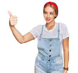 Obraz na płótnie Canvas Young caucasian girl wearing casual clothes looking proud, smiling doing thumbs up gesture to the side