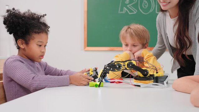 Smart primary students grouping to learning robot free electives with female teacher in classroom. Teacher female teach children assemble robot in science subject at elementary school.