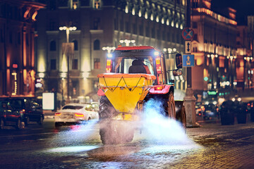 Tractor with salt spreader plow snow, spread salt on pavement after snow storm, road maintenance -...