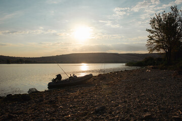 a boat with fishing rods on the shore of the lake at dawn in the morning