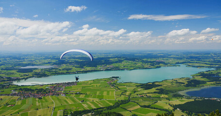 Hang glider flies above lake Forggensee in Bavaria, Germany