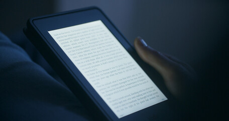 A woman reading an e-book in the evening or by night - 687539438