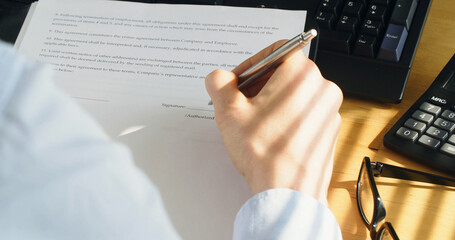 Female employee reading and signing a contract (dummy signature).