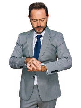 Middle age man wearing business clothes checking the time on wrist watch, relaxed and confident