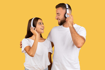 Smiling young european man in white t-shirt and lady in wireless headphones, listen music