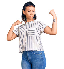 Young woman wearing casual clothes showing arms muscles smiling proud. fitness concept.