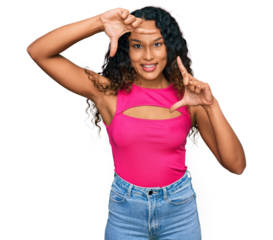 Young hispanic woman with curly hair wearing pink top smiling making frame with hands and fingers with happy face. creativity and photography concept.