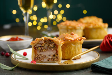 Festive portioned British meat pies with chicken, pork and becon on a dark background. Christmas...