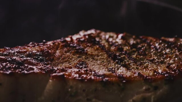 Seasoned tomahawk steak is cooked in a frying pan.