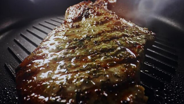 Seasoned tomahawk steak is cooked in a frying pan.