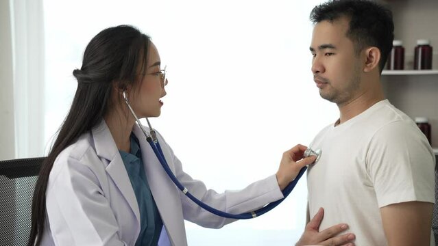 Beautiful female doctor uses stethoscope to listen to heart and lung function, man in hospital with stethoscope. Health problems, illness concept.Video 4k