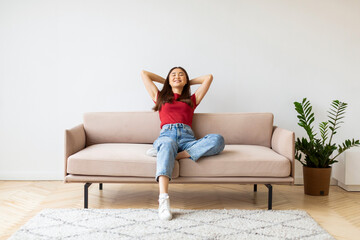 Obraz premium Home Comfort. Portrait Of Smiling Young Asian Woman Leaning Back On Couch