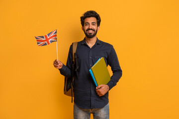 Language Courses. Smiling Young Indian Man Holding British Flag And Workbooks
