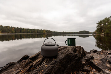 Coffee kettle and mug on stone by lake