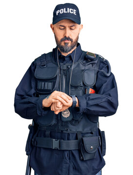 Young handsome man wearing police uniform checking the time on wrist watch, relaxed and confident