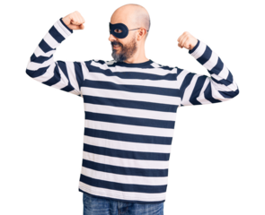 Young handsome man wearing burglar mask showing arms muscles smiling proud. fitness concept.