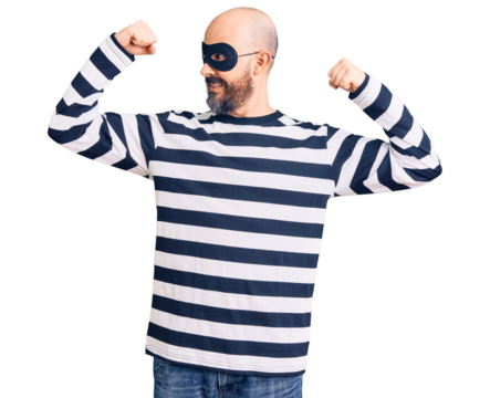 Young handsome man wearing burglar mask showing arms muscles smiling proud. fitness concept.