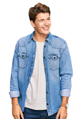 Handsome caucasian man wearing casual denim jacket looking away to side with smile on face, natural expression. laughing confident. - obrazy, fototapety, plakaty