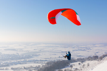 Gleitschirmfliegen im Winter über der verschneiten Stadt