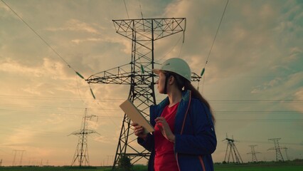 Women-engineer hard hat with tablet computer look power line. Concept energy business technology industry. Delivery electric energy consumer. Electrical technician of diagnosis power transmission