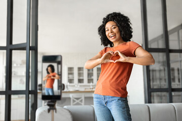 Black Woman Making Heart Sign At Camera While Recording Video At Home