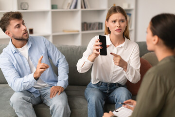 Jealous wife shows smartphone with empty screen to psychologist indoor