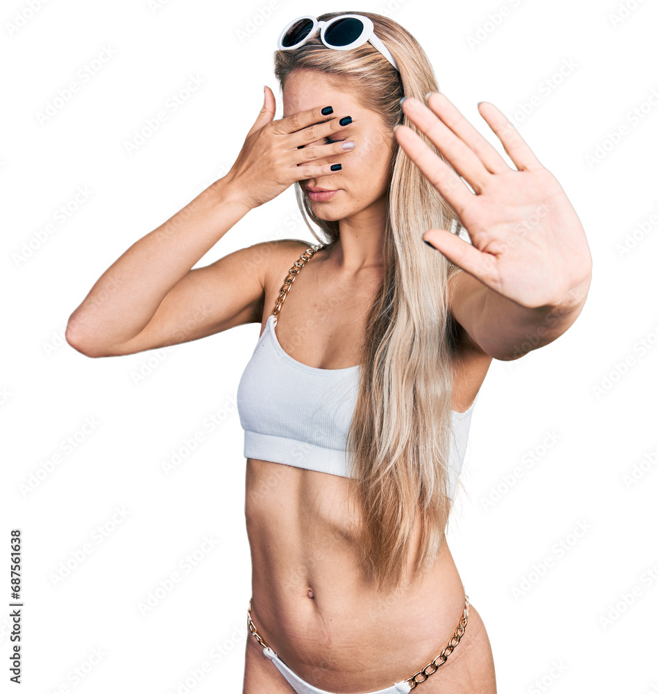 Poster Beautiful young blonde woman wearing bikini covering eyes with hands and doing stop gesture with sad and fear expression. embarrassed and negative concept.