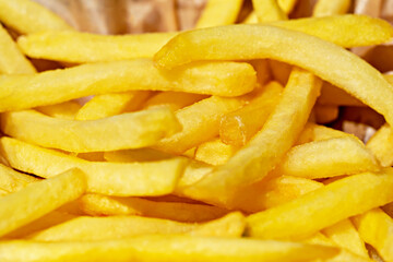 Fresh tasty fried french fries in paper bag close up. Selective focus, defocus