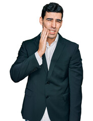 Handsome hispanic man wearing business clothes touching mouth with hand with painful expression because of toothache or dental illness on teeth. dentist