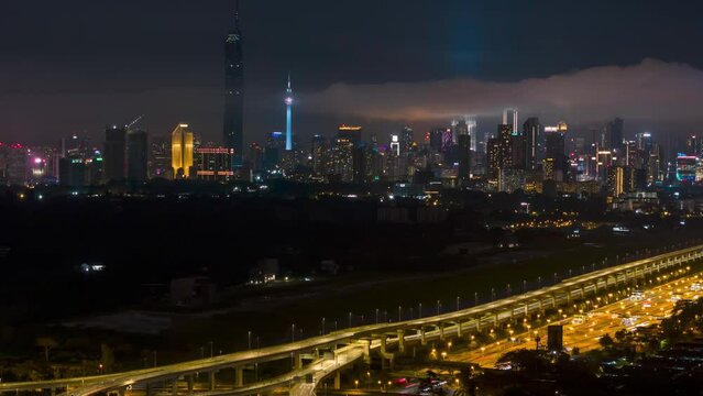 Cinematic aerial drone night scene hyperlapse of Kuala Lumpur city skyline with elevated highway, residential and city skyline. Pan right