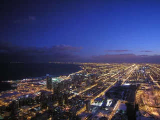 Zelfklevend Fotobehang A panoramic aerial view of the urban landscape of Chicago and Lake Michigan at night with vibrant lights, modern architecture, and clouds. © Ali Chehade