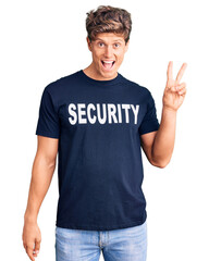 Young handsome man wearing security t shirt smiling looking to the camera showing fingers doing victory sign. number two.