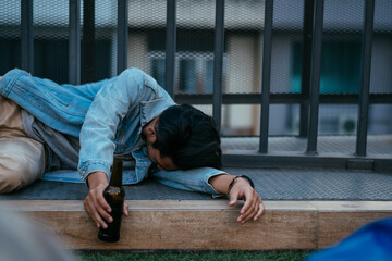 Asian sleepy drunk man holding beer bottle and lying on floor after nightlife party event, hangover lonely young adult concept for birthday, New Year, disappointed work, sadness or heartbroken - obrazy, fototapety, plakaty