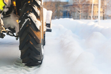 The rear wheel of a harvesting equipment standing on the snow without moving. Back view. Cleaning...