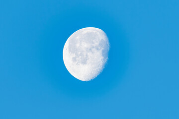 Brightly lit Waning Gibbous moon in blue sky