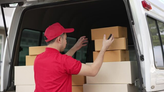 Handsome Asian man holding a cardboard parcel box standing in front of a house with a van in the background, delivery concept. 4K resolution.