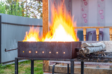 Fire with birch wood in a barbecue for grilling kebabs meat on fire in the summer evening on the...