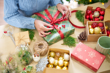Woman in knitted sweater wrapping christmas presents with eco paper girl packing christmas gifts Xmas holiday concept