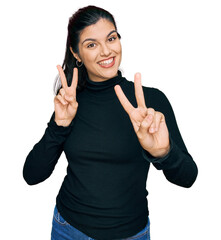 Young hispanic woman wearing casual clothes smiling looking to the camera showing fingers doing...