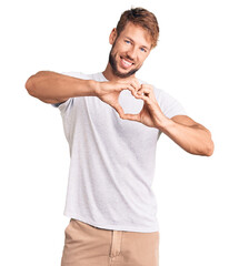 Young caucasian man wearing casual white tshirt smiling in love doing heart symbol shape with hands. romantic concept.