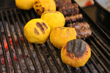 Balls of polenta named bulz with cheese in the middle of it cooked on a grill.