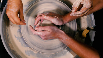 Close-up of a female potter's hands moulding and shaping a stunning piece of white clay pottery....
