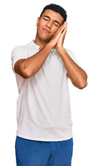 Young arab man wearing casual clothes sleeping tired dreaming and posing with hands together while smiling with closed eyes.